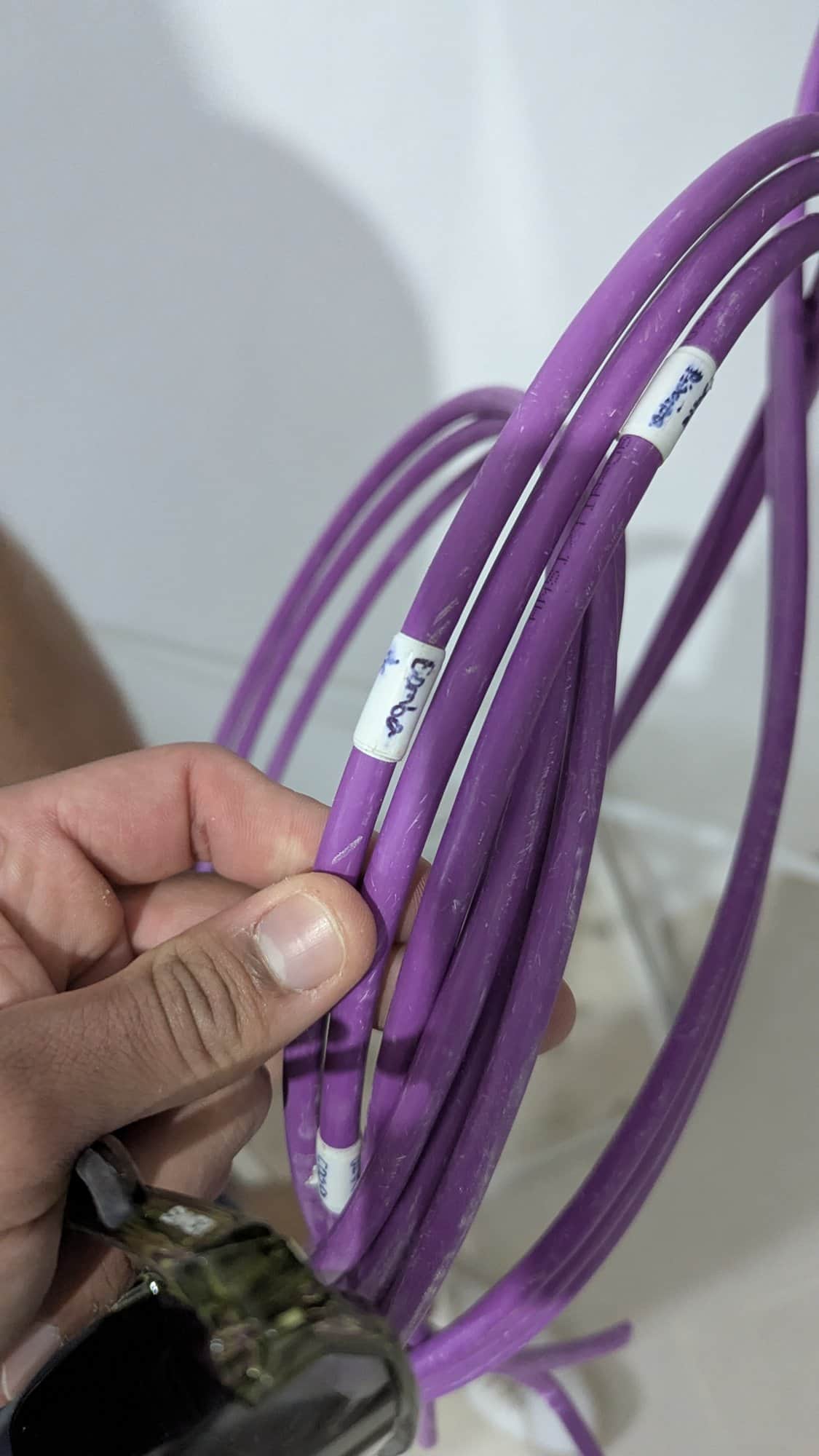 Bundel buskabels, elk voorzien van een handgeschreven label per ruimte.